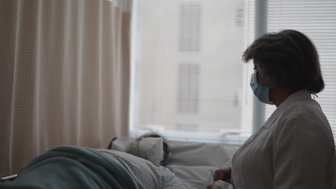 医生戴着防护口罩在病房里和病人交谈视频素材
