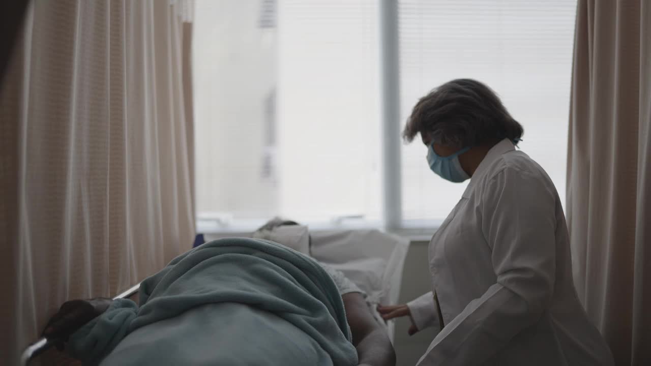 医生戴着防护口罩在病房里和病人交谈视频素材