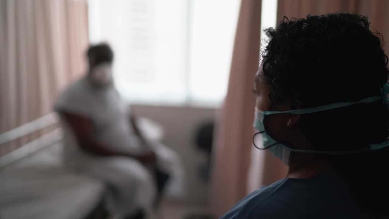 护士戴着防护口罩在病房与病人交谈视频素材