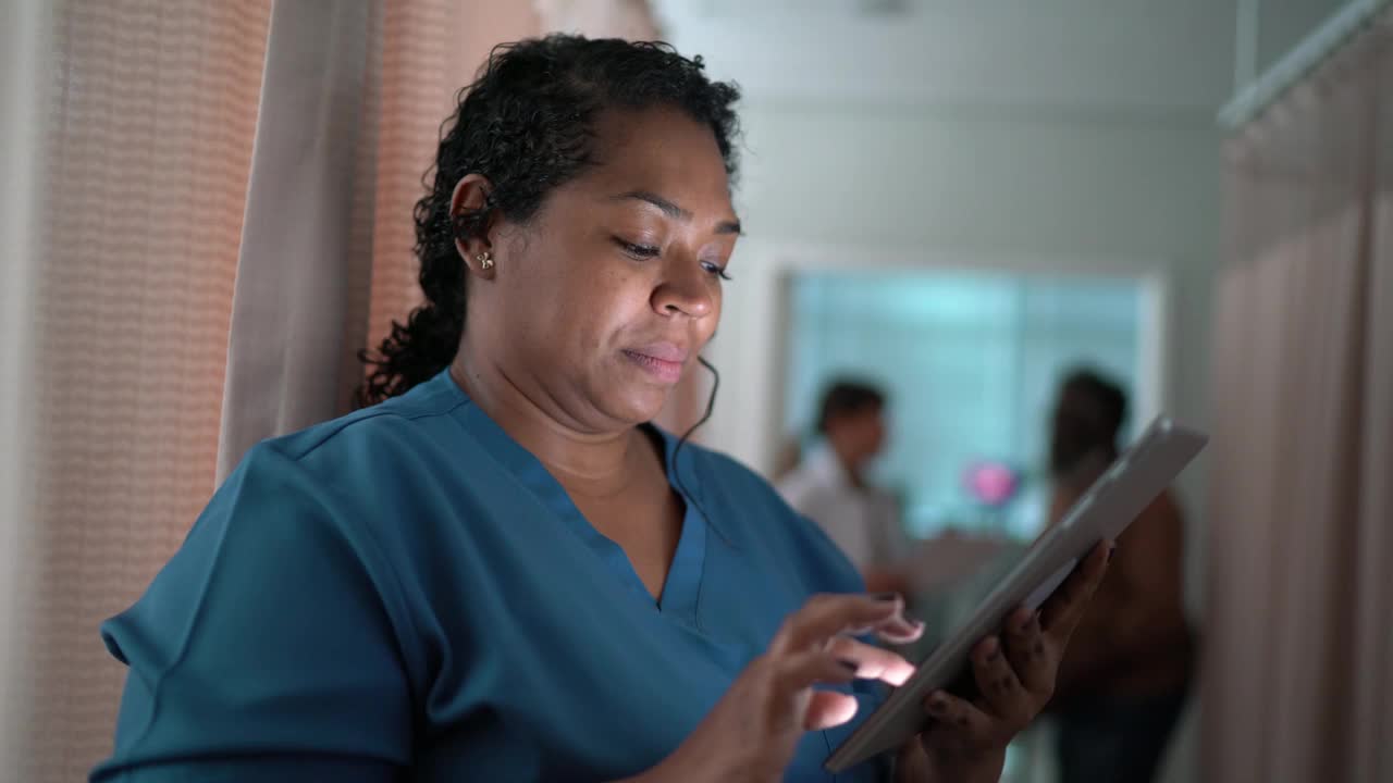 一个快乐的护士在医院使用电子平板电脑视频下载