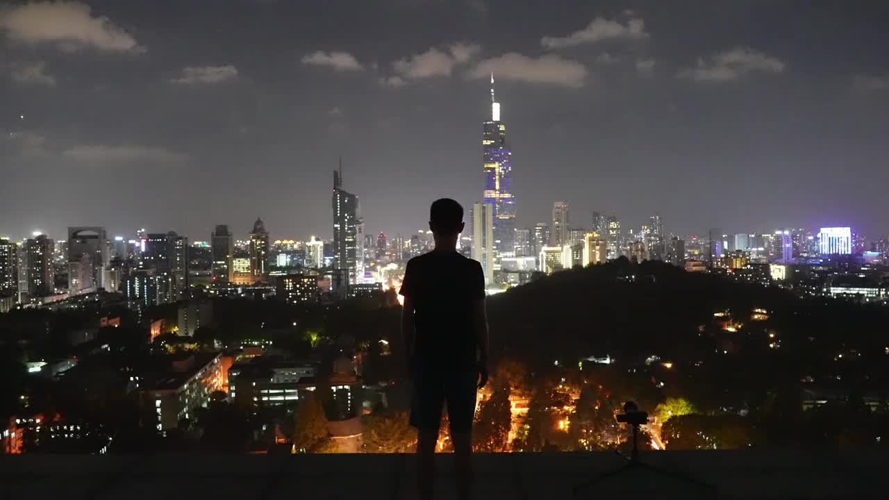一个男人在夜晚的屋顶上张开双臂视频素材