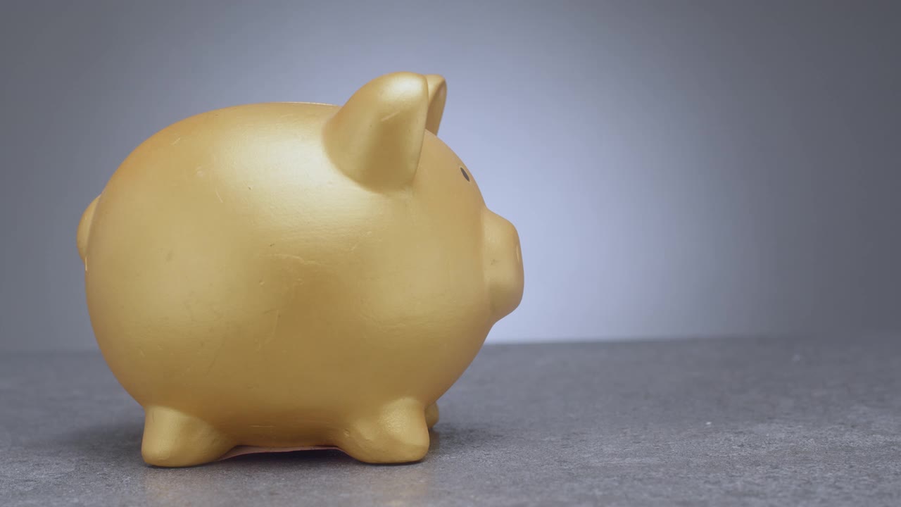 用一个金色的小猪储蓄罐存钱。视频下载
