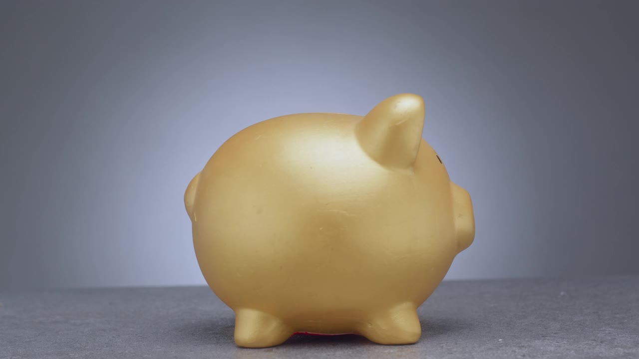 用一个金色的小猪储蓄罐存钱。那女人把手伸进一枚硬币视频下载