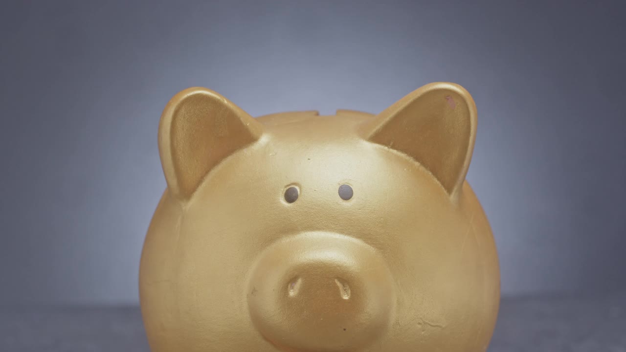 用一个金色的小猪储蓄罐存钱。视频下载