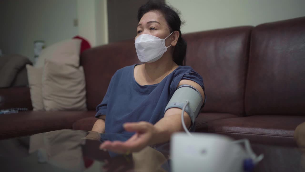 亚洲高级妇女在家中测量血压。视频下载