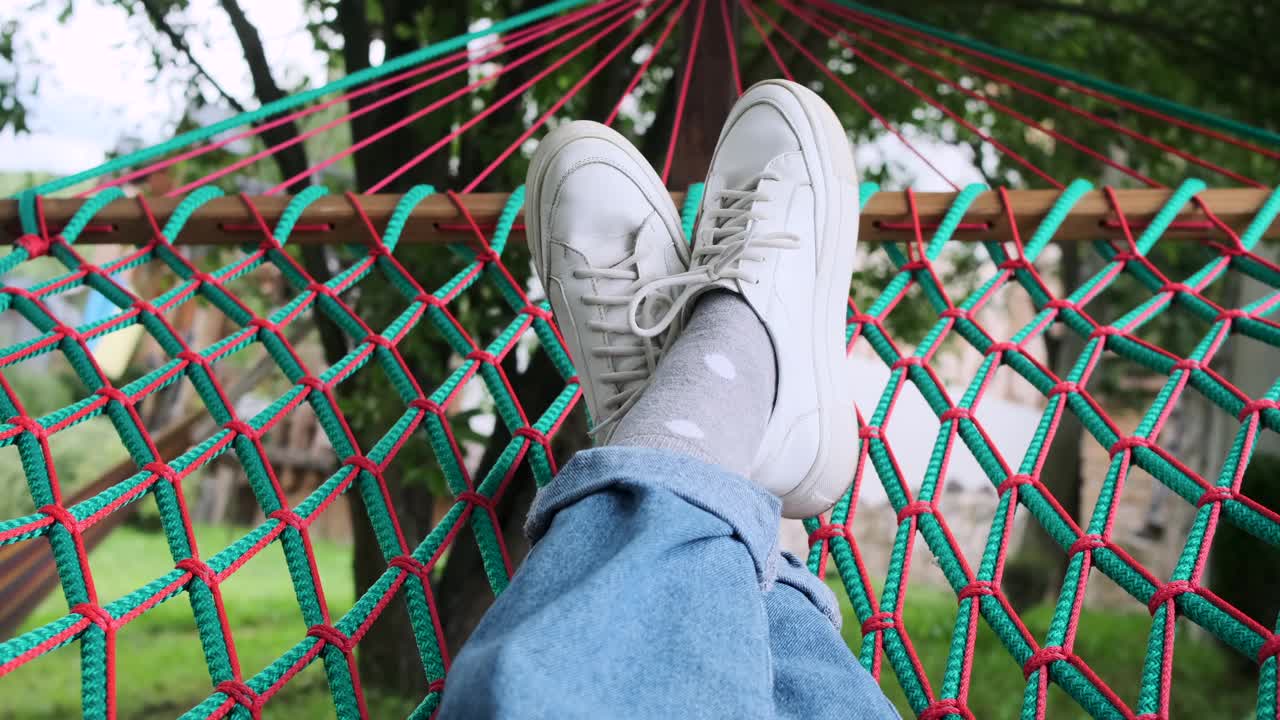 穿着白鞋的女人的腿躺在吊床上视频下载