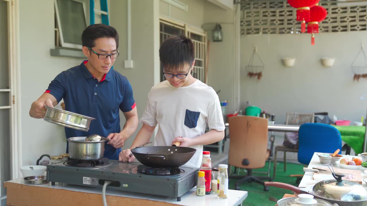 亚洲华人父亲和儿子一起在潮湿的厨房后院周末准备晚餐视频下载