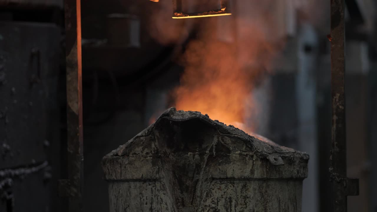 熔化金属液，操作人员努力工作，将熔化的金属液从炉中出到钢包，然后浇注到铸造厂视频素材