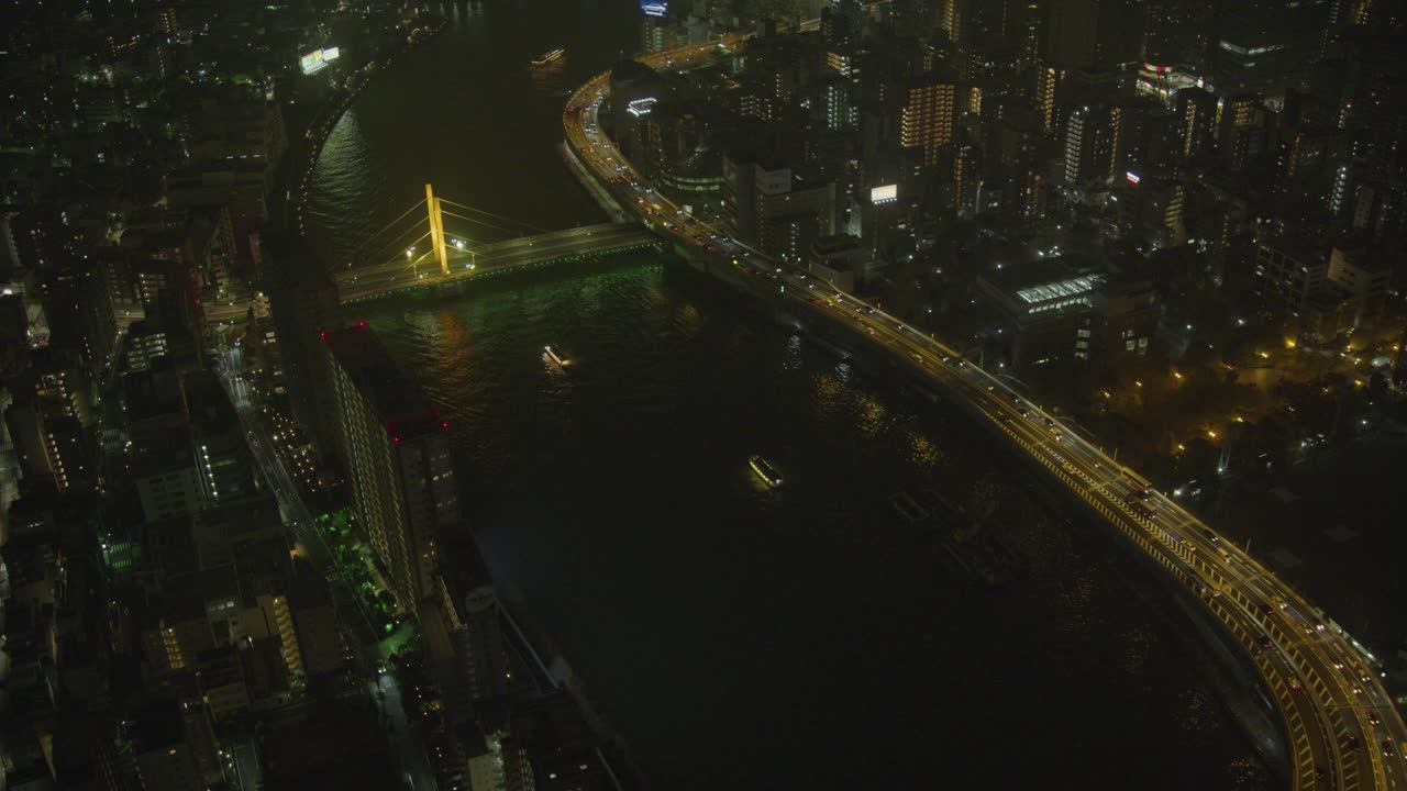 横跨东京隅田河的天桥。高速公路或公路桥横跨河流。城市的天际线可以看到高楼大厦、摩天大楼、办公楼和公寓楼。河上可见的渡船或船只。视频下载