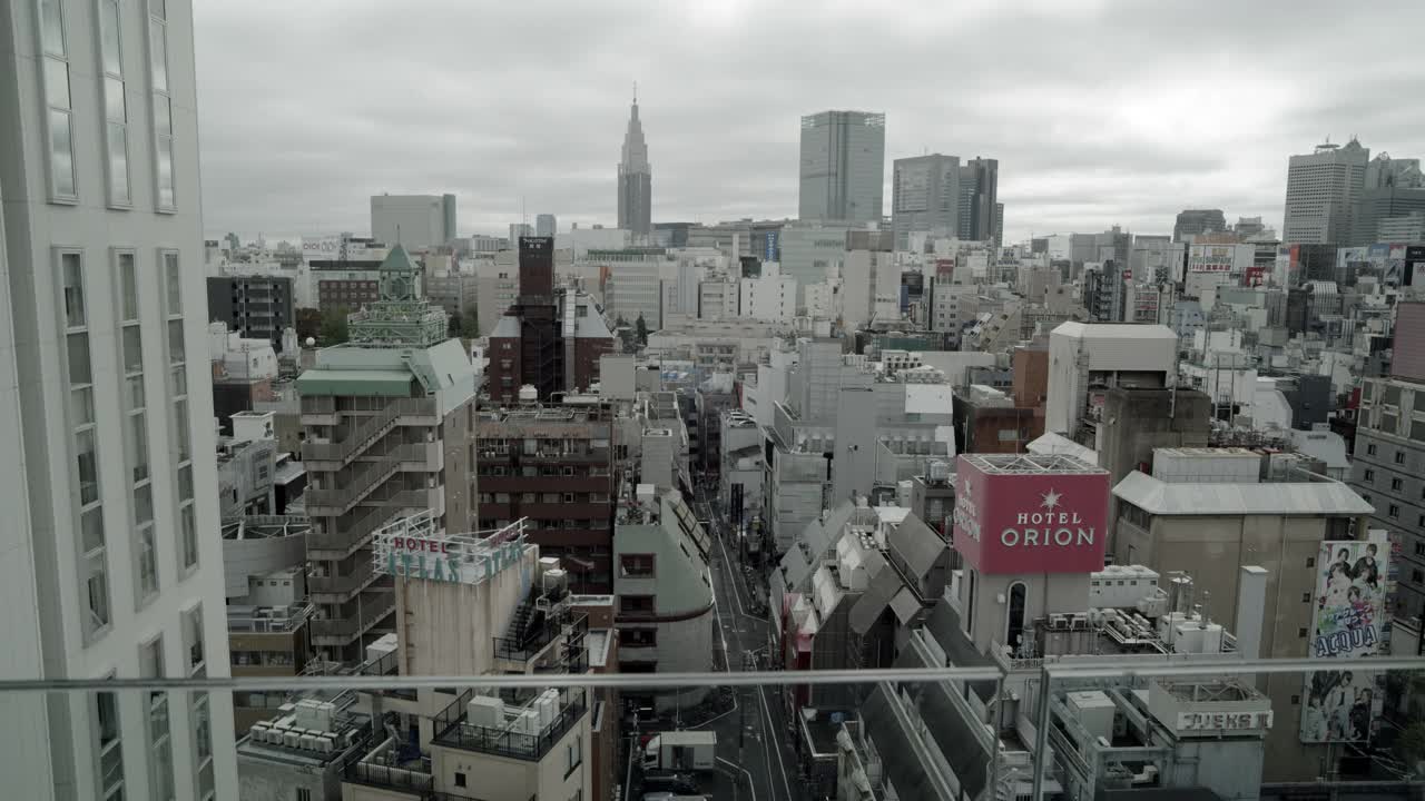 从建筑物的阳台上看东京城市天际线的中等角度。可能是酒店或办公楼。其他的高层建筑、公寓楼和摩天大楼都可见。Docomo代代木建筑和mode gauken茧塔部分可见。视频素材