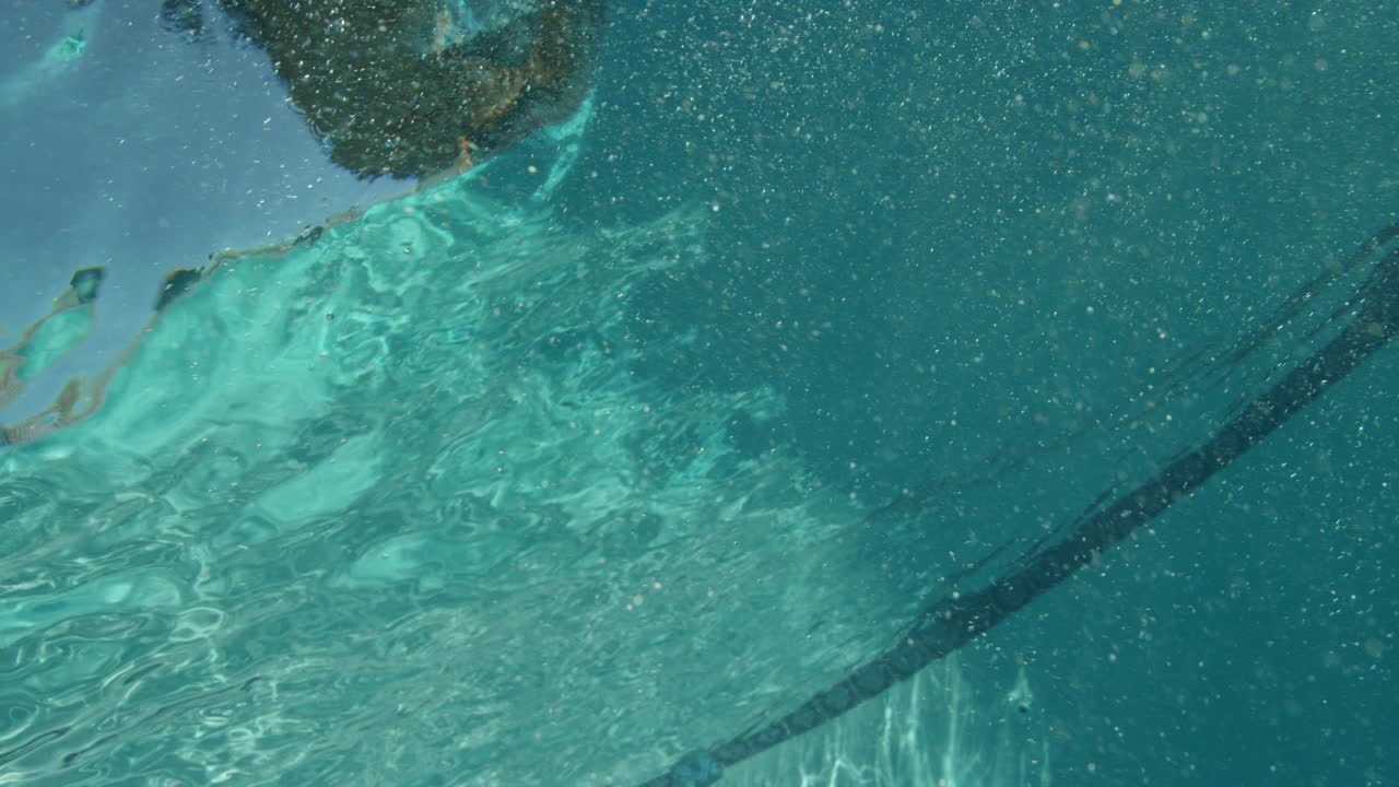 游泳池中气泡的水下中角。水池墙上可见蓝色瓷砖。视频素材