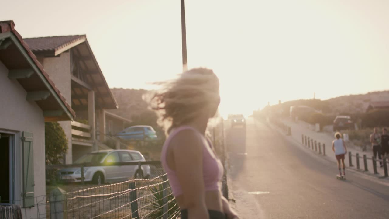 年轻女子背着滑板在日落视频下载