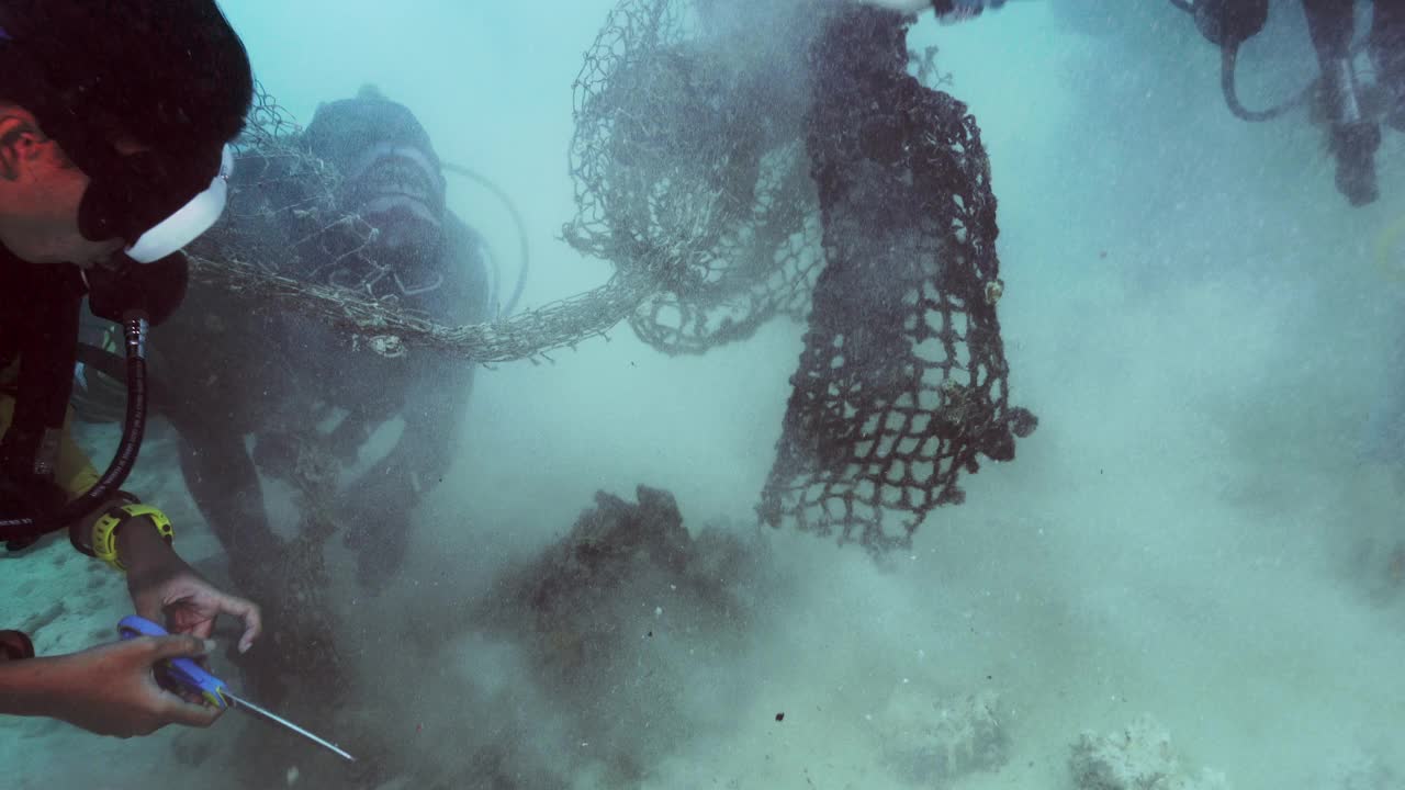 水下环保人士用水肺潜水员清理缠结的渔网视频素材