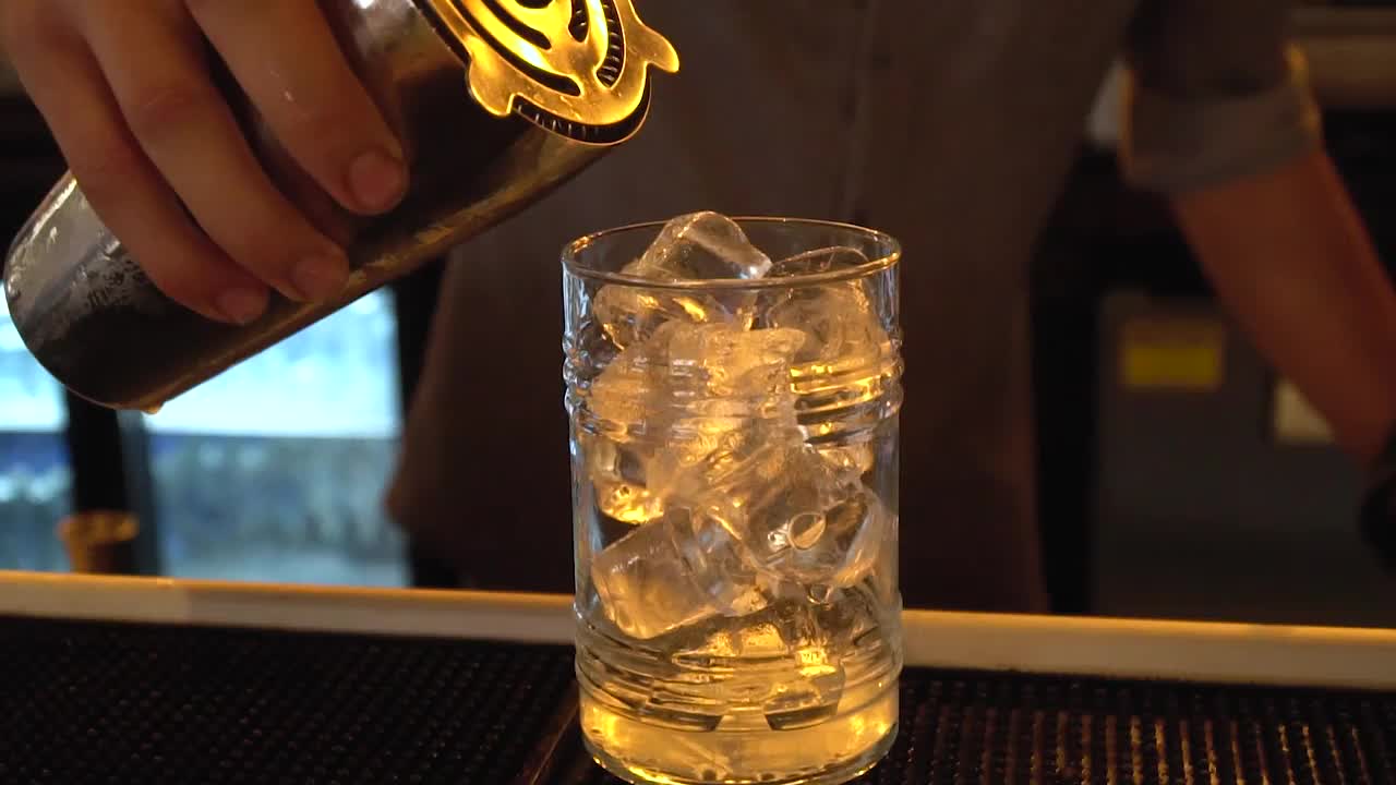 橙汁被冰倒在玻璃杯中，背景是敏感的焦点视频素材