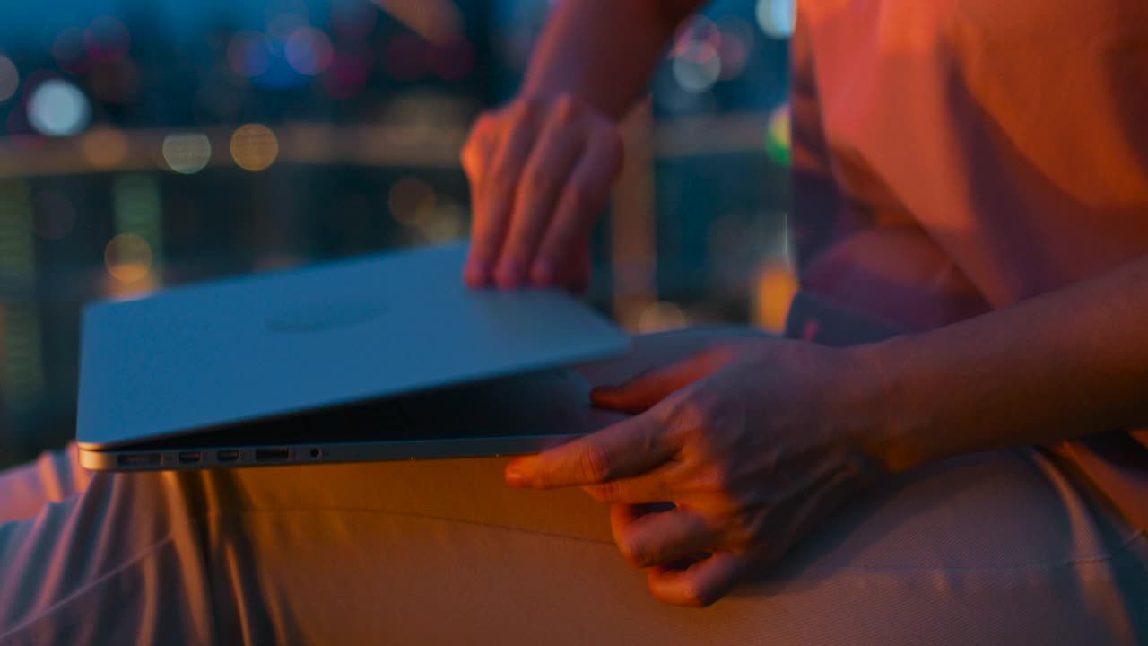 一个年轻女人的手在城市之夜用笔记本电脑视频素材