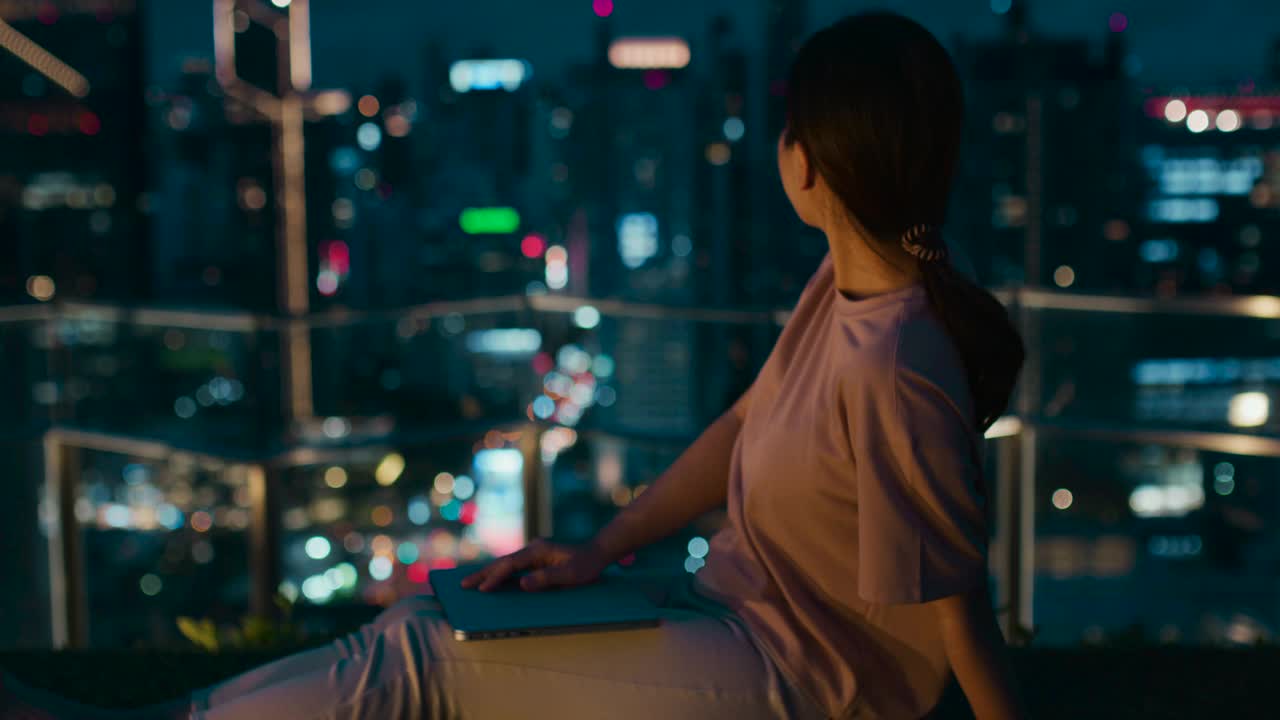 一个年轻女人的手在城市之夜用笔记本电脑视频素材