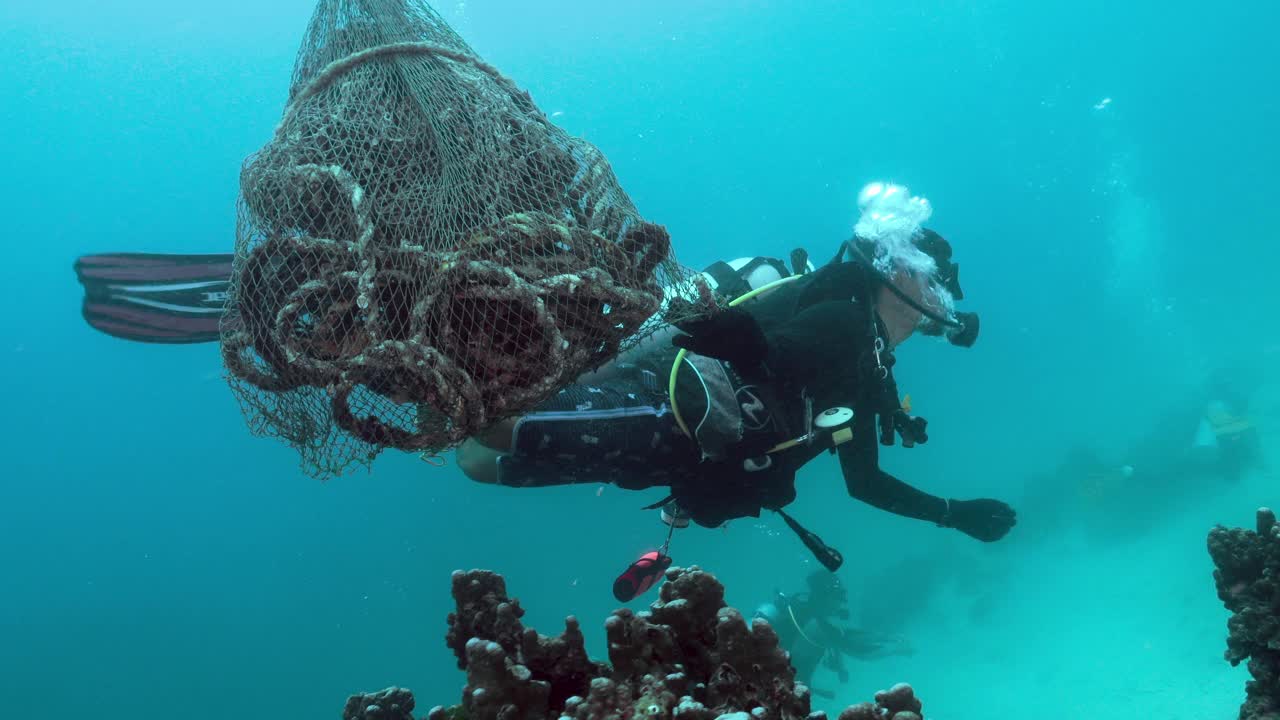 戴着水肺的潜水员用袋子把泰国水下的渔网收集起来视频素材