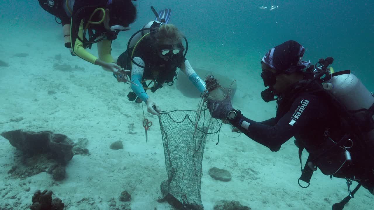 戴水肺的潜水员在水下清理废弃的渔网视频素材