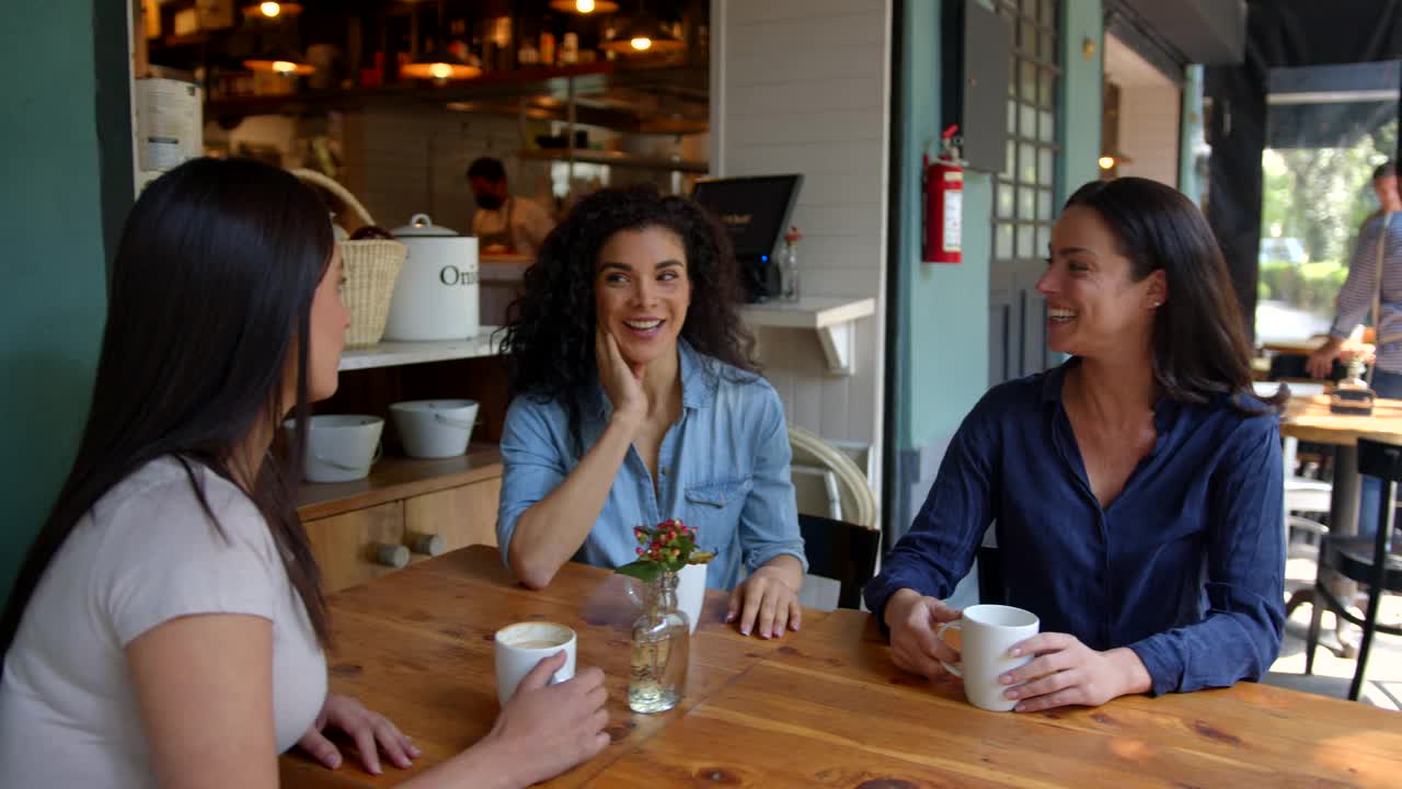 一群美丽的女性朋友在餐厅边喝咖啡边谈笑风生视频素材