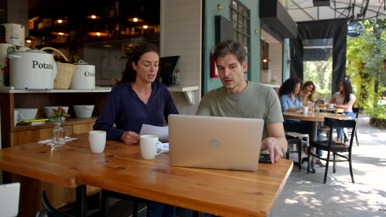 一对商业夫妇在咖啡店边讨论边用笔记本电脑工作视频素材