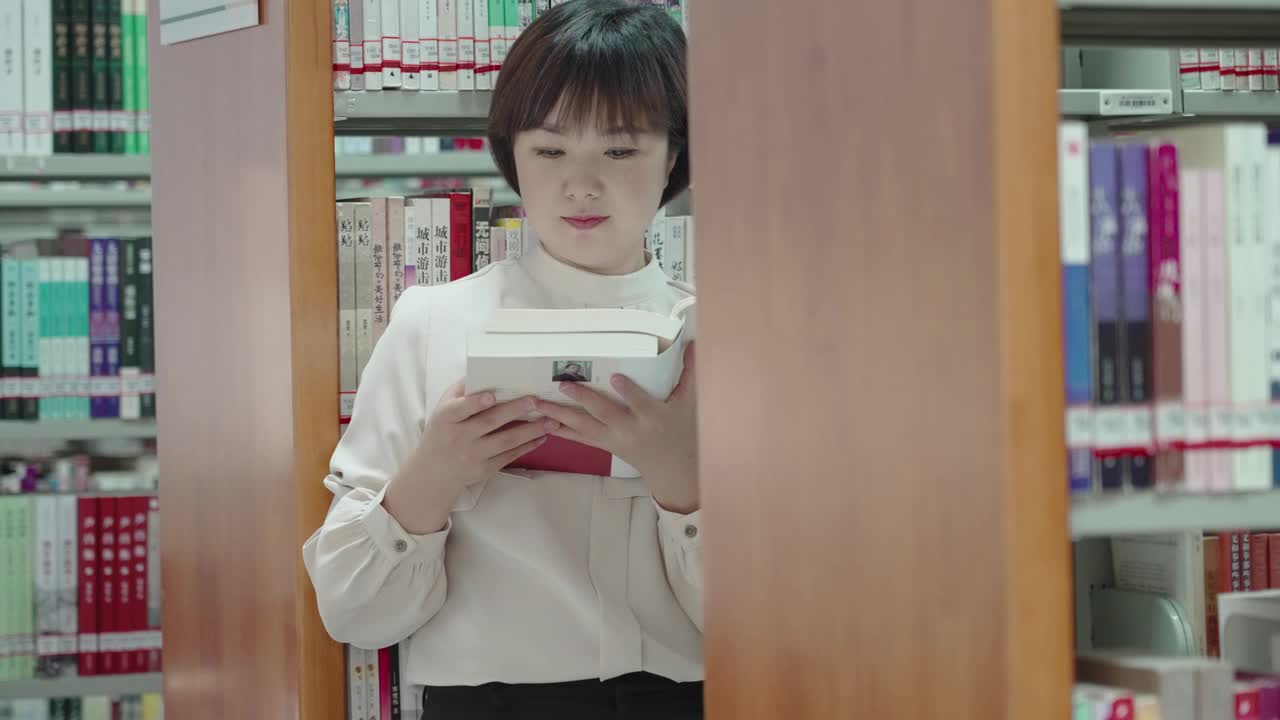 亚洲女人在图书馆的书架上看书视频素材