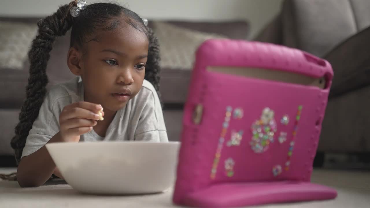 一个小女孩在平板电脑上看节目视频素材