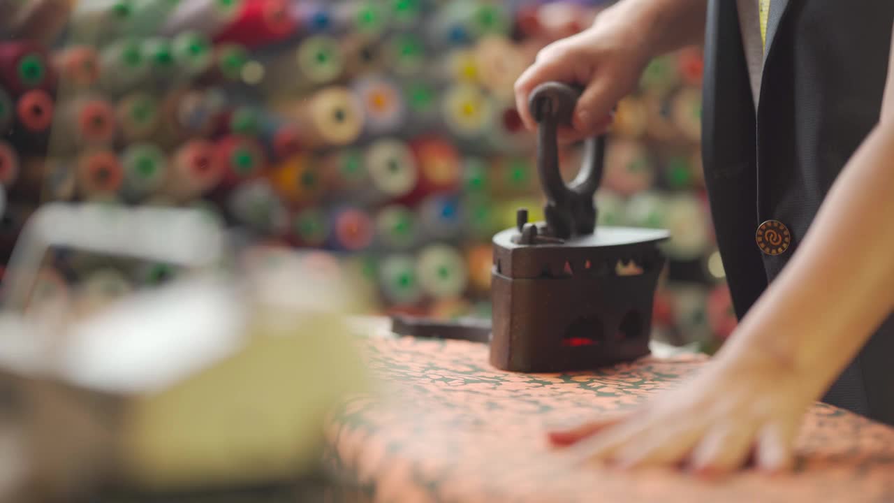 近距离拍摄亚洲华人高级妇女裁缝手用传统古玩铁器具在她的工作室熨布视频下载