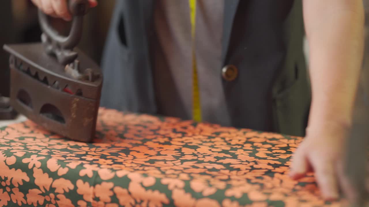 近距离拍摄亚洲华人高级妇女裁缝手用传统古玩铁器具在她的工作室熨布视频下载