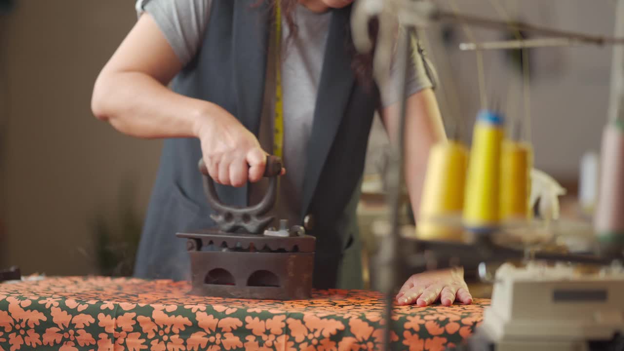近距离拍摄亚洲华人高级妇女裁缝手用传统古玩铁器具在她的工作室熨布视频素材