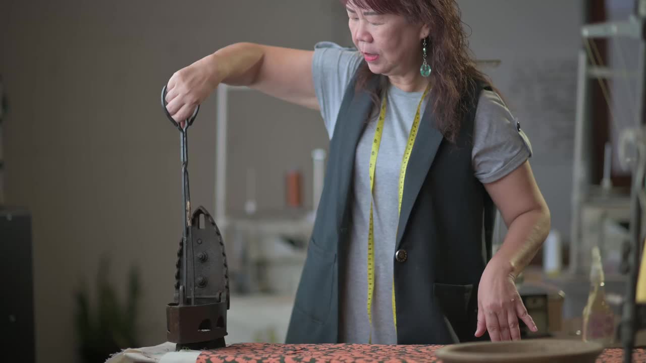 亚洲中国高级妇女裁缝拿起滚烫的木炭从陶器与服务钳放入古董铁传统熨烫视频下载