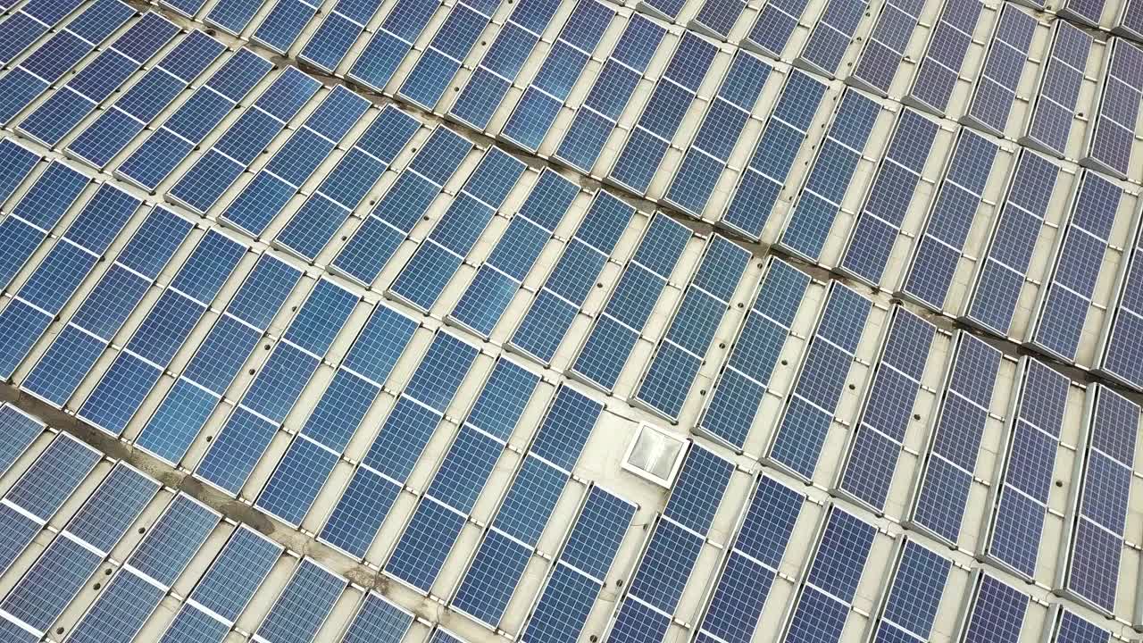 工业建筑屋顶安装蓝色光伏板的太阳能发电厂鸟瞰图。视频素材