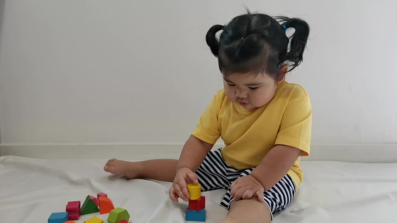 亚洲小女孩在地板上玩木块。视频素材