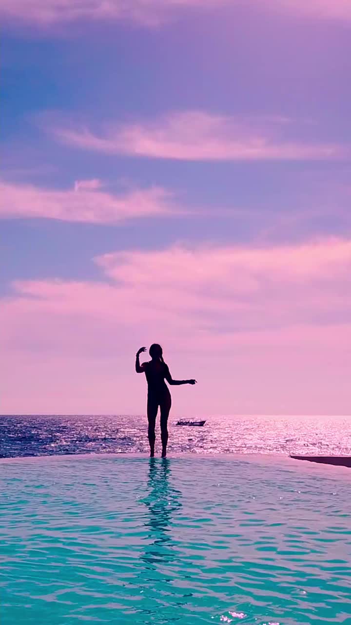 在大海的映衬下，一个年轻的女孩在水池边跳舞。视频下载