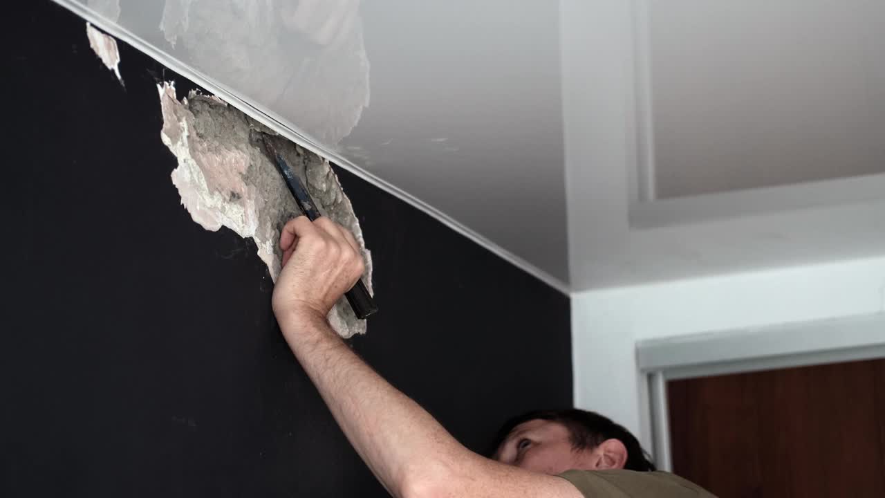 人在家里修理，并用锤子和凿子破坏混凝土墙。慢动作视频素材