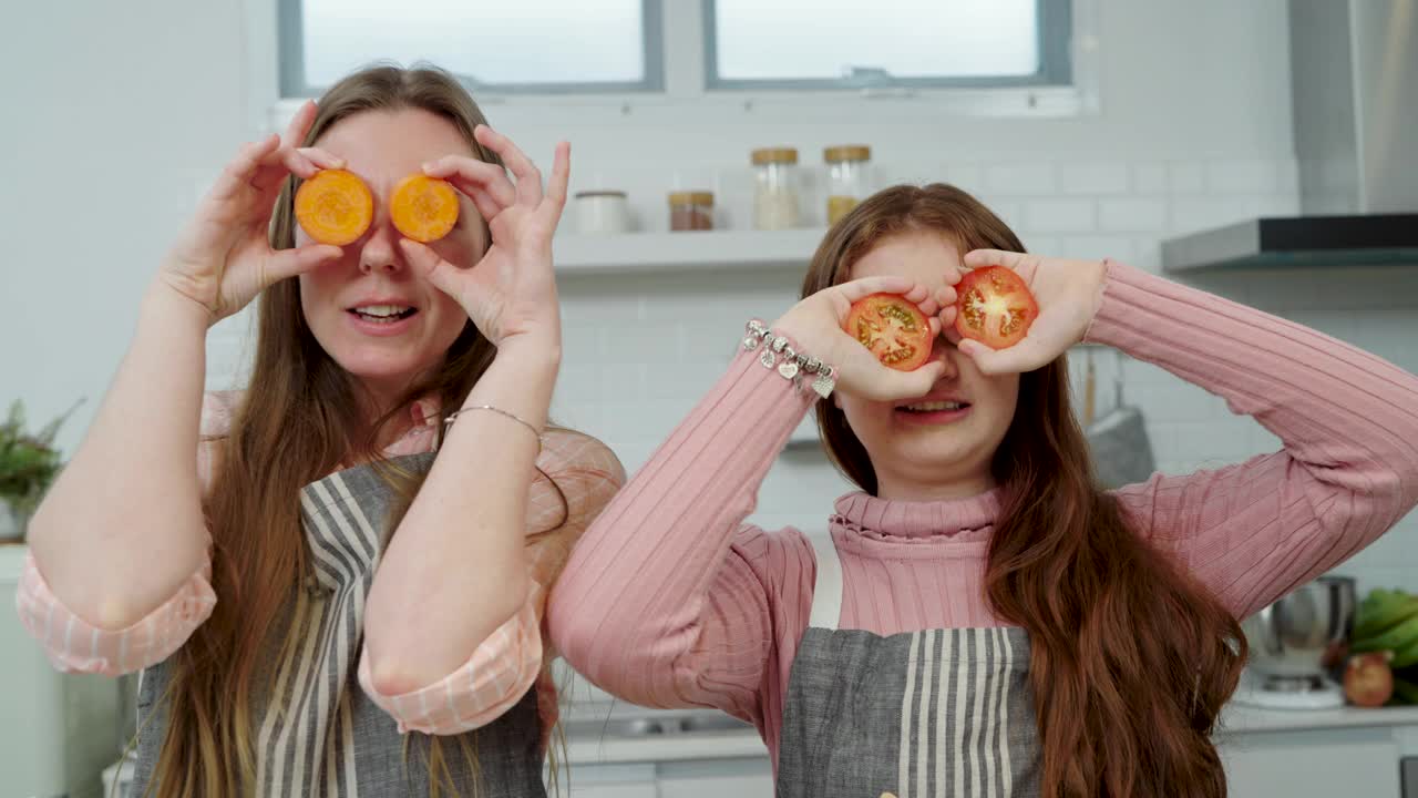 女人和少女在橘子或胡萝卜旁闭上眼睛。妈妈和女儿在厨房准备食物视频下载