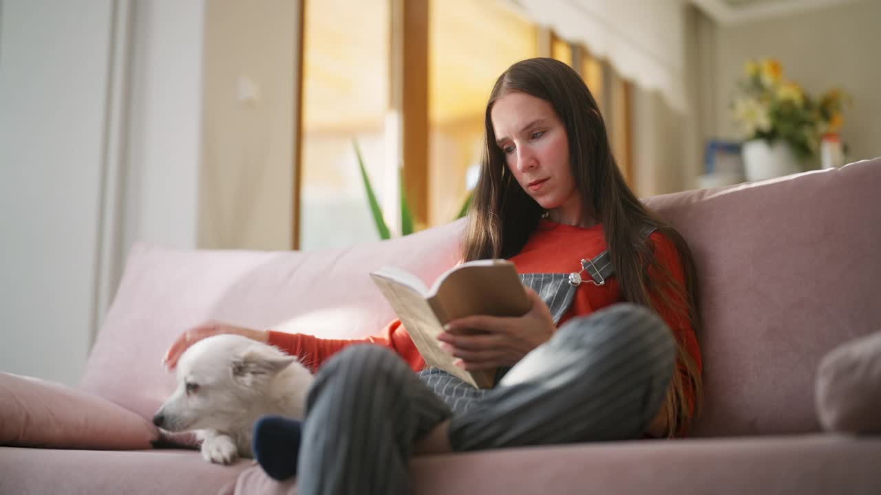 一个女人和她的狗在家里的客厅里读书视频下载