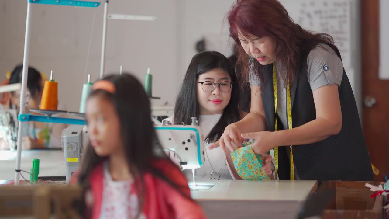 亚洲华人成熟女性裁缝在她的工作室里教她的缝纫班学生缝纫技巧视频下载