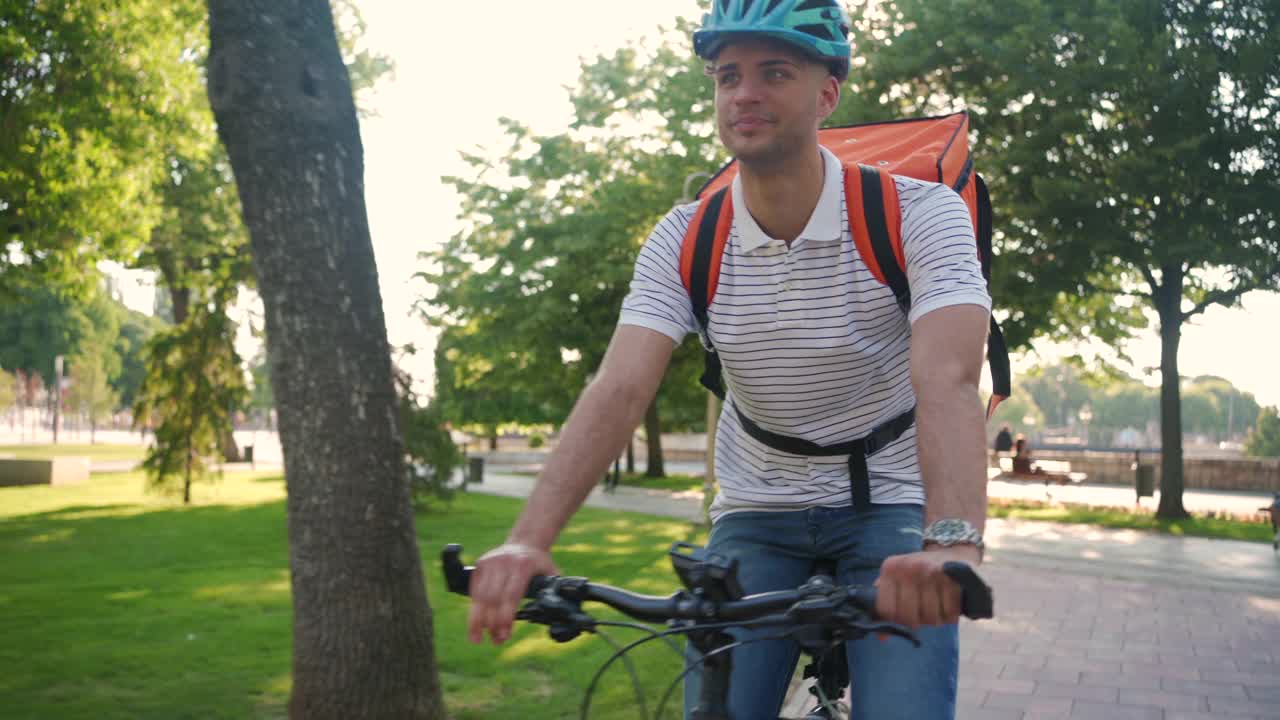骑着自行车在城里送食物的送货员的后视图视频素材