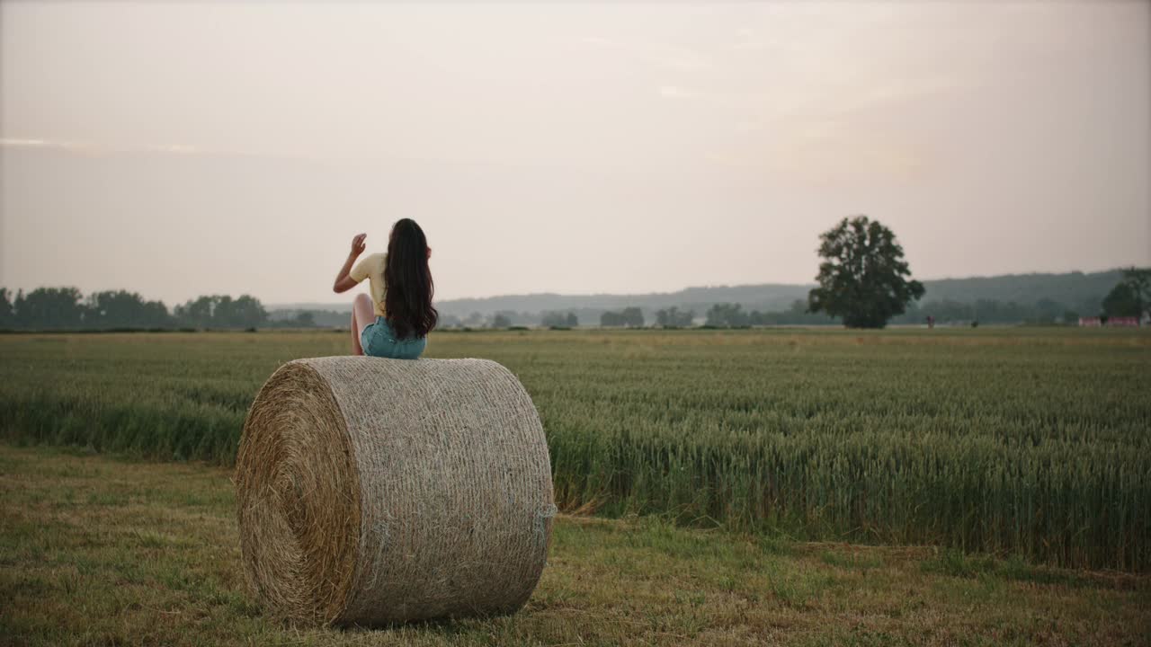 一个年轻的女人坐在一捆干草上视频素材
