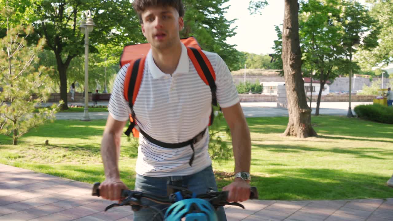 一个年轻的送货员骑着自行车在城里送食物视频素材