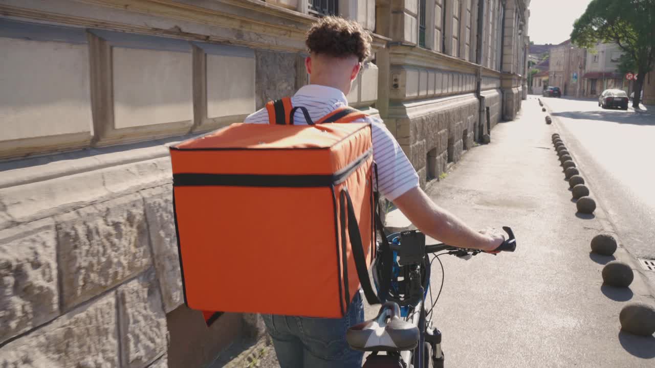 骑自行车在城里送食物的外卖员的后视图视频素材