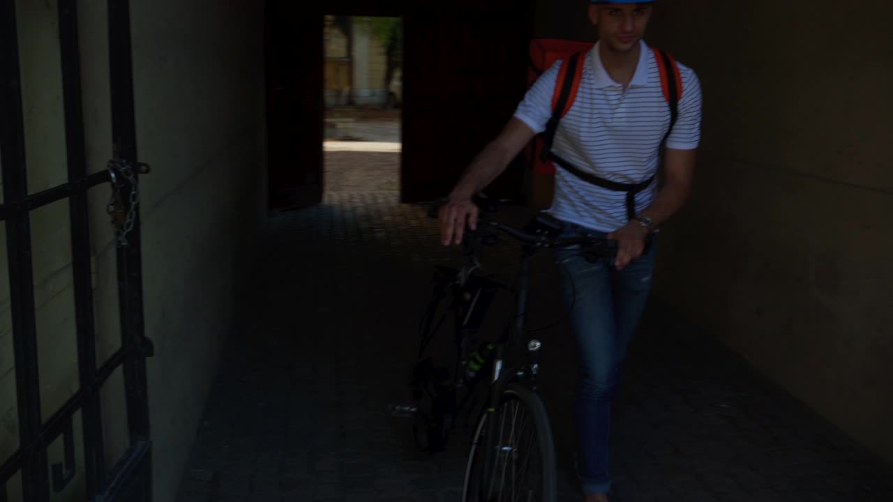 微笑着骑着自行车的外卖员在城里送食物视频素材