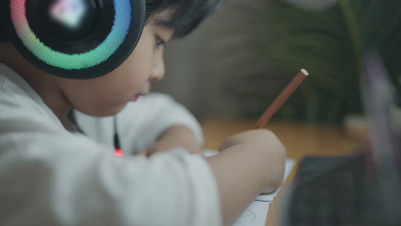 一个戴着耳机在家学习的男孩视频素材