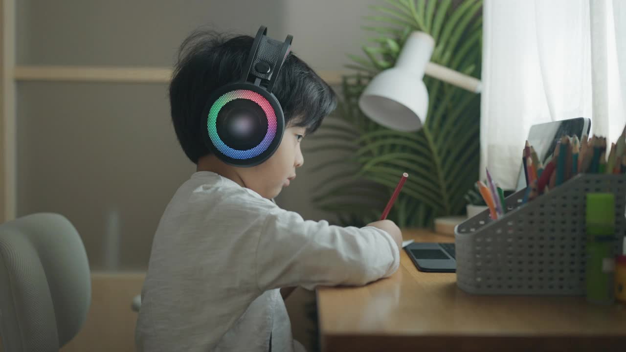 一个戴着耳机在家学习的男孩视频素材