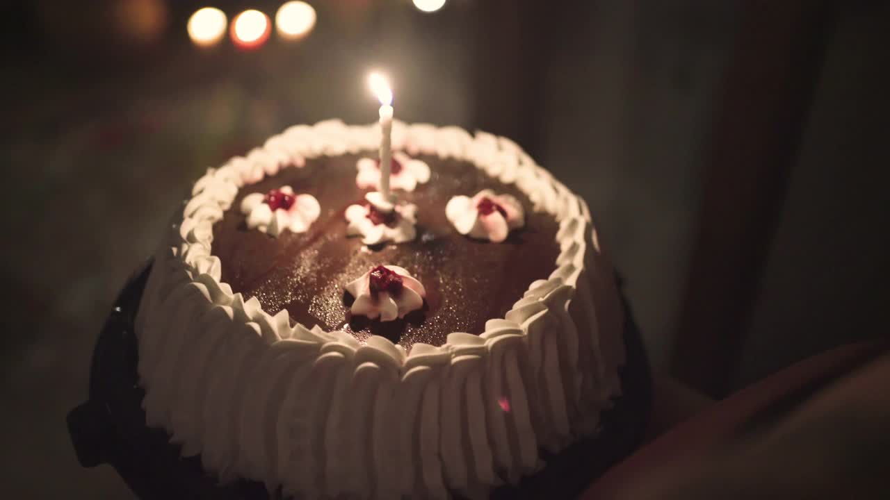 一个快乐的年轻女人吹着生日蛋糕上的蜡烛，她的朋友拿着蛋糕给她一个惊喜视频下载