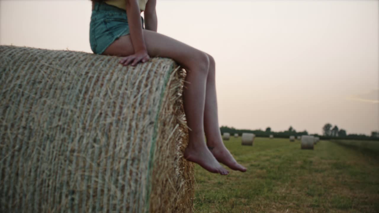 一位年轻女子坐在一捆干草上的腿视频素材