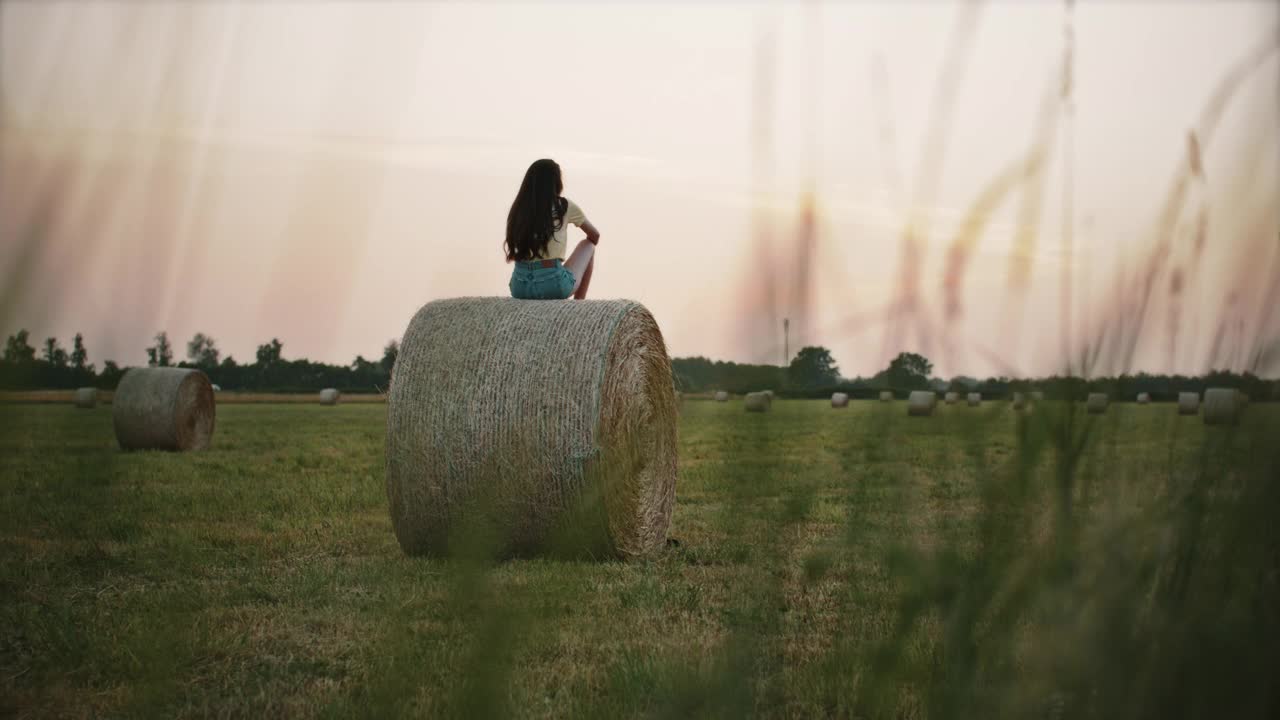 一个年轻的女人在一捆干草上休息视频素材
