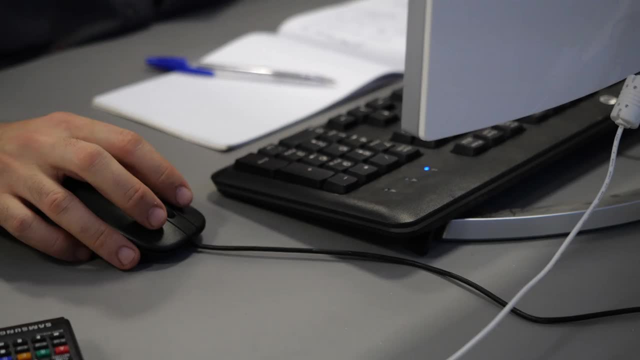员工在办公室桌子前用鼠标在电脑上工作视频素材