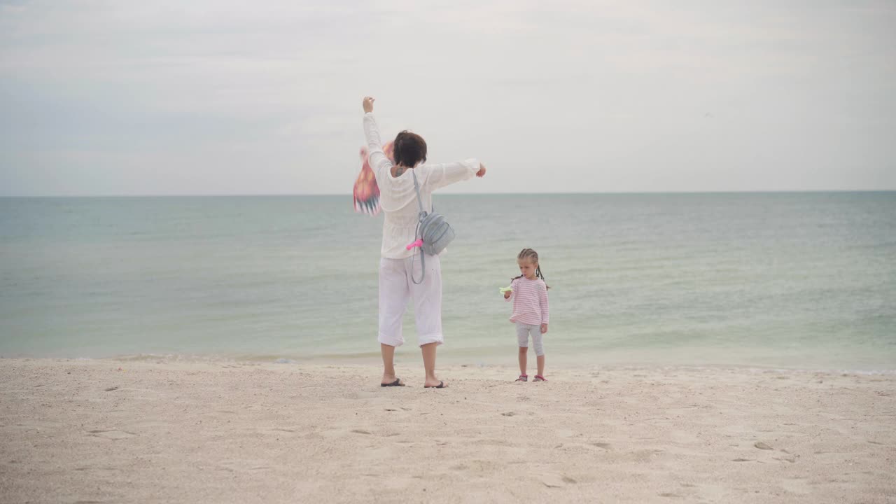 妈妈和小女儿在海边玩风筝快乐的高加索家庭和一个孩子在海边玩暑假视频素材