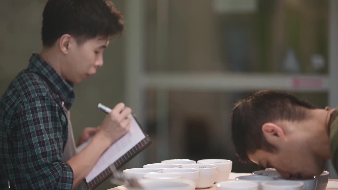 2专业亚洲中国高级男人咖啡鉴赏家年级表演咖啡拔火罐写下剪贴板后品尝咖啡和他的同事拔火罐视频素材